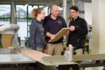 Ausbildung im BTZ Osnabrück: Tischler Meister erklärt Holz an Säge.